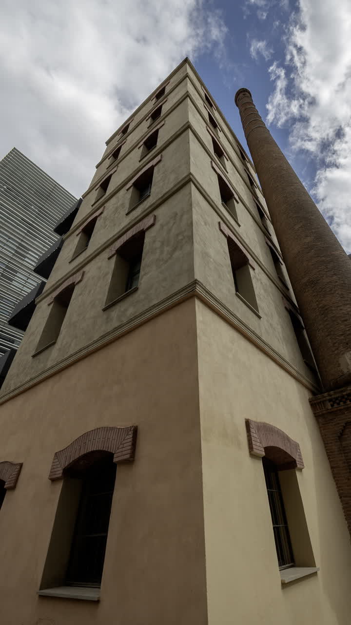 Old factory chimney and apartment buildings in barcelona in vertical