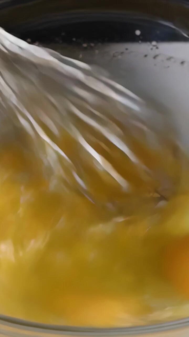 Video verticale: Sbattendo tre uova in una ciotola di vetro sul bancone, frusta che entra e mescola per la cottura