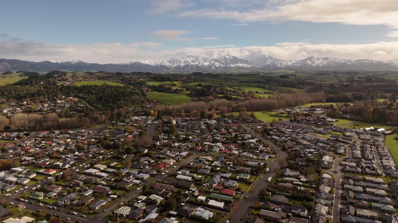 Geraldine town with green hills and majestic snow-capped Southern Alps in background, New Zealand. Aerial drone view