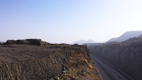 toma aérea de una encuesta para el trabajo de tuberías y la construcción, viendo una carretera pública dividida por acantilados de montaña