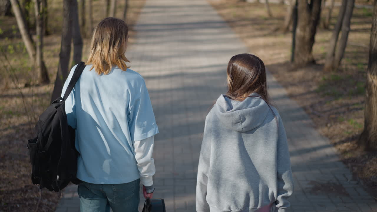 야외에서 산책하는 친구들, 자연 속에서 걷는 두 동반자, 봄에 평화로운 산책을 즐기는 친구 한 쌍, 따뜻한 봄에 나무가 늘어선 자갈길을 따라 하이킹하는 두 사람