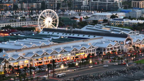 Toma-Aérea-Del-Famoso-Centro-Comercial-Y-De-Entretenimiento-En-El-Paseo-Marítimo-Al-Atardecer.-Revelando-Edificios-En-El-Distrito-Urbano.-Ciudad-Del-Cabo,-Sudáfrica