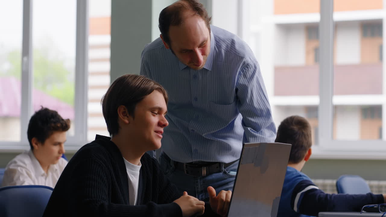 maestro ayudando al estudiante con una computadora portátil en el aula