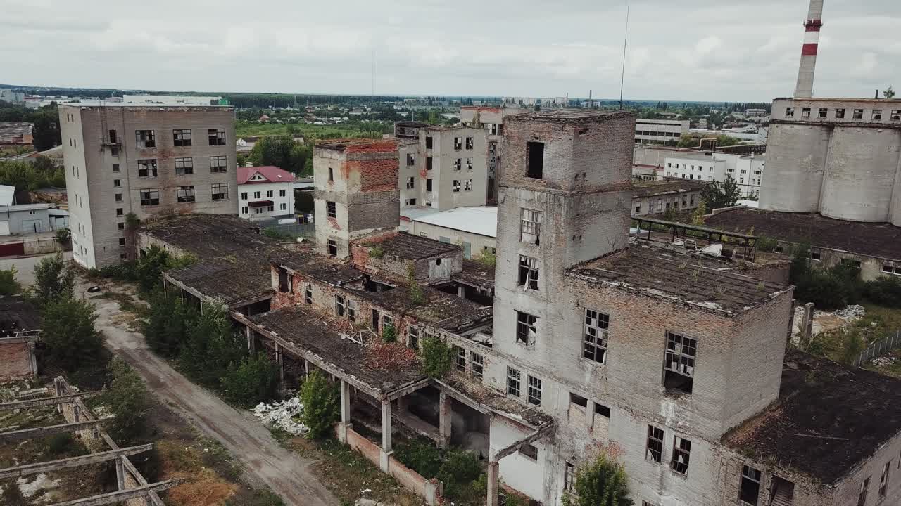 Ruins of an old factory. Abandoned building was covered with grass and trees. Holes and cracked in the walls and ceiling. Aerial view