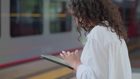 woman using a tablet at a train station