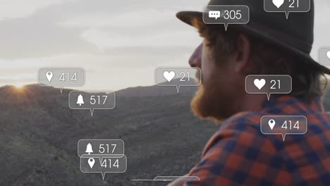man sitting on rocky hillside at sunset, with floating social media marketing notification icons