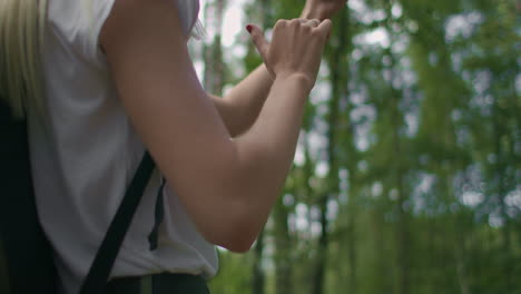 close-up of a woman holding a mobile phone walking through the woods traveling with a backpack in slow motion. navigate through the forest using the navigator in your mobile phone