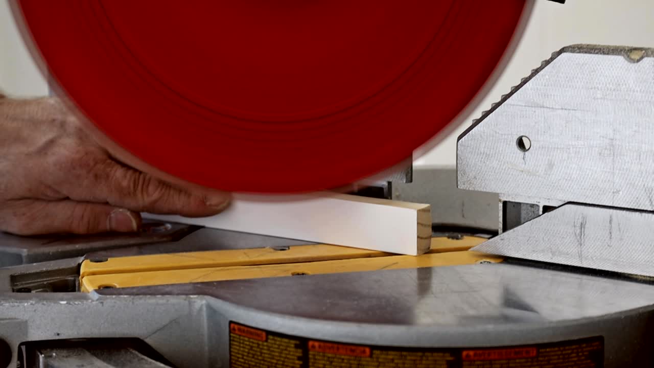 joven carpintero guapo usando una sierra circular mientras instala madera en la construcción de una nueva casa