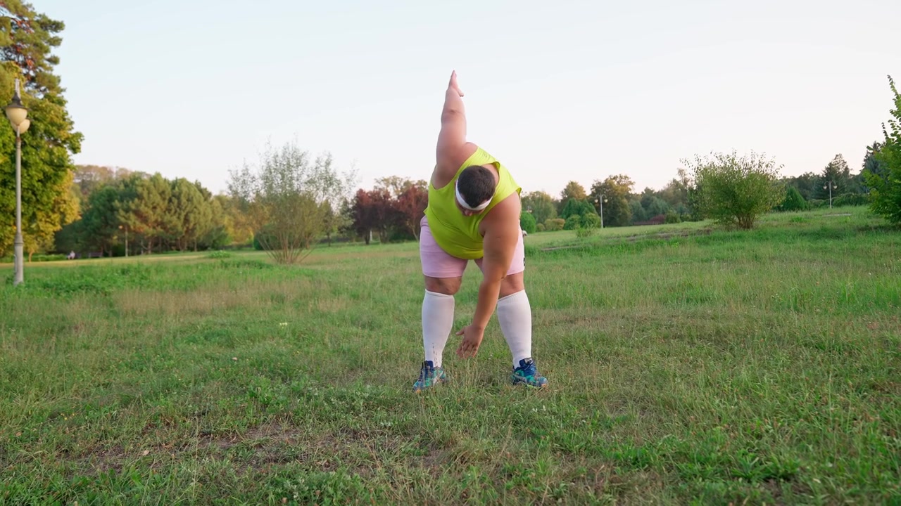 Uomo in sovrappeso che fa stretching in un parco verde