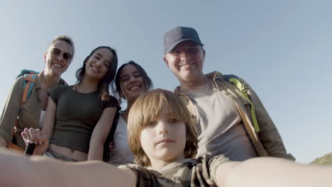 POV-of-a-little-boy-holding-camera-taking-selfie-of-his-family-outdoors