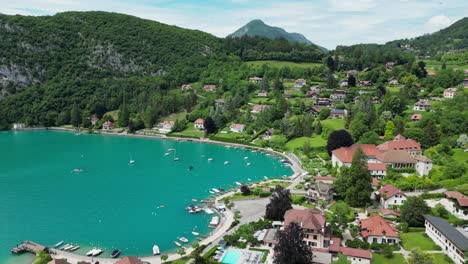 turquoise blue lake annecy and talloires village in french alps - aerial