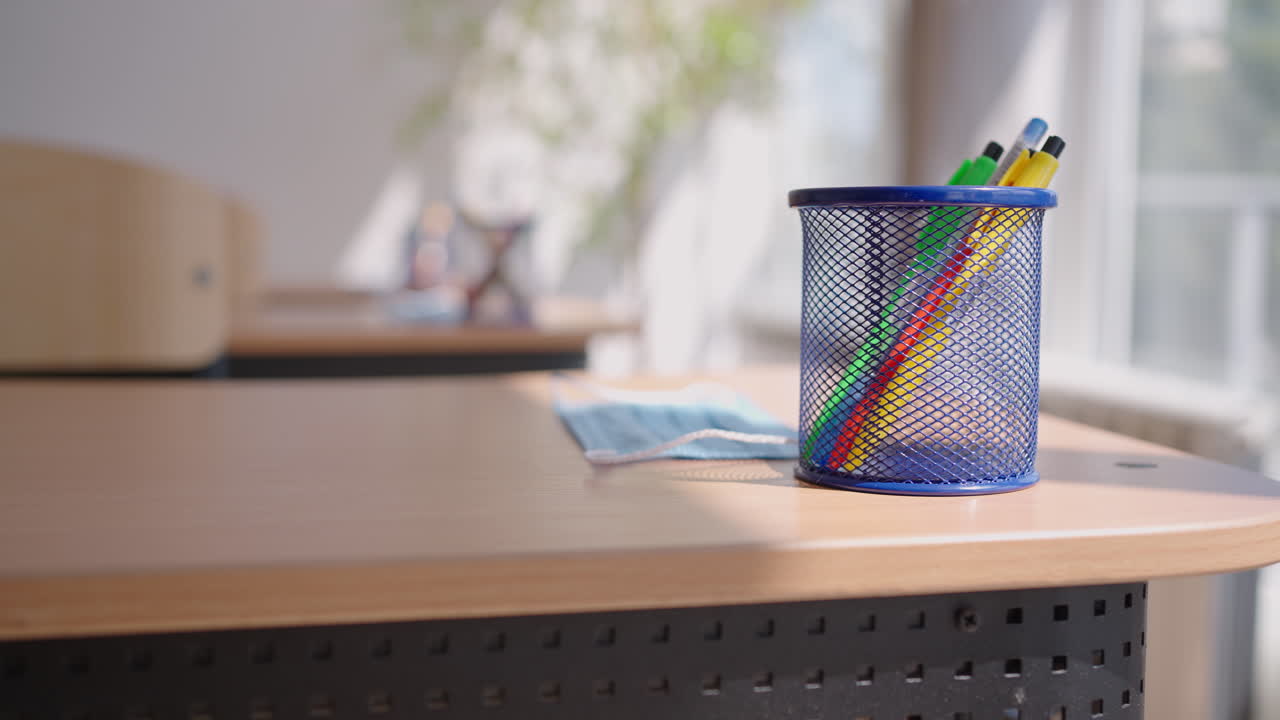 лучи света падают на пустую темную классную комнату. камера смотрит за рядами столов и стульев. учительский класс без учеников во время перерыва. заброшенная школа. тревожное настроение.