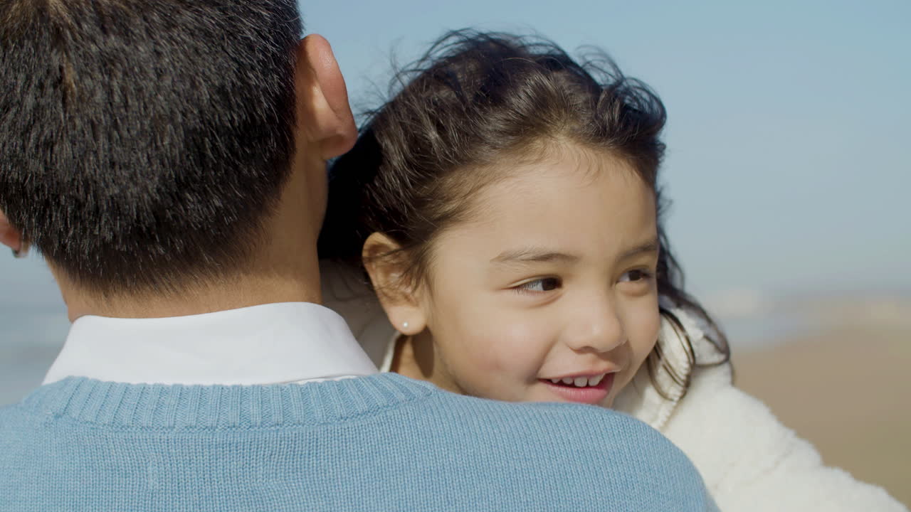 primer plano de una linda niña japonesa feliz abrazando a su padre en la playa