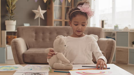 girl with toy bear drawing