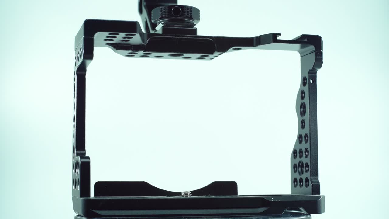 360도 회전 스탠드, 스튜디오 조명, 슬로우 모션, 4k 위에 핸들러가 있는 검은색 금속 카메라 케이지의 클로즈업 샷, 비디오 제작 장비