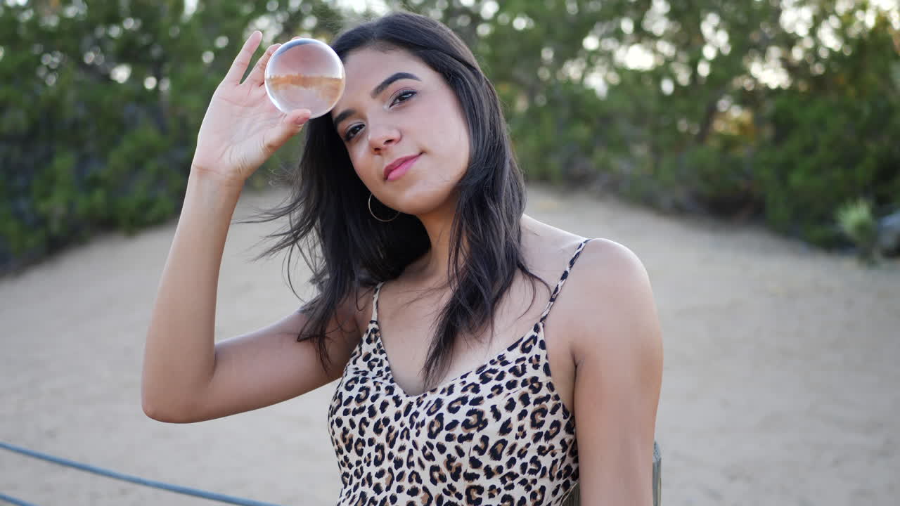 una hermosa mujer hispana sosteniendo una bola de cristal mágica y sonriendo a cámara lenta