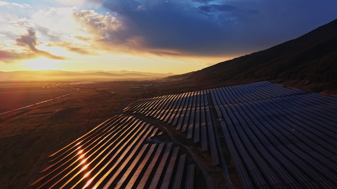 Solpaneler i dalen fanger sollys ved solnedgang i bjergene