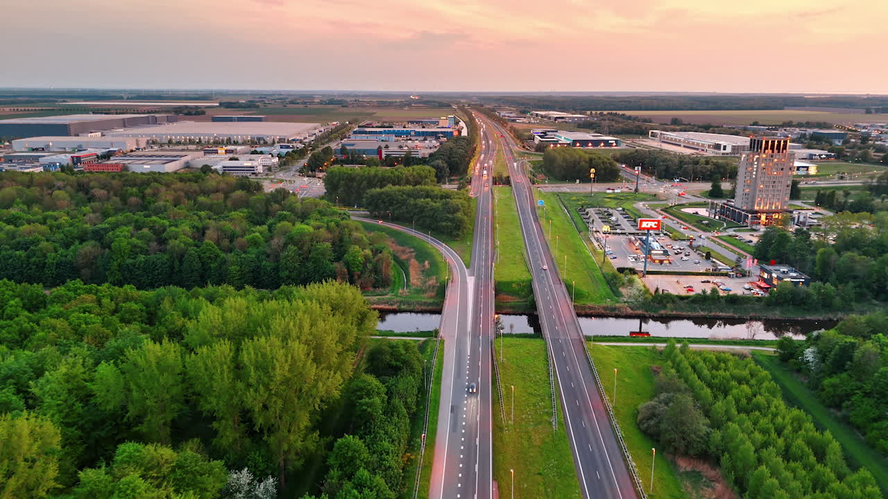 Sunset over Dutch highway. Aerial perspective of a highway in the Netherlands during sunset, showcasing greenery and developed areas