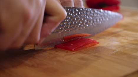 el chef corta pimiento rojo grande en la tabla de cortar, en la cocina