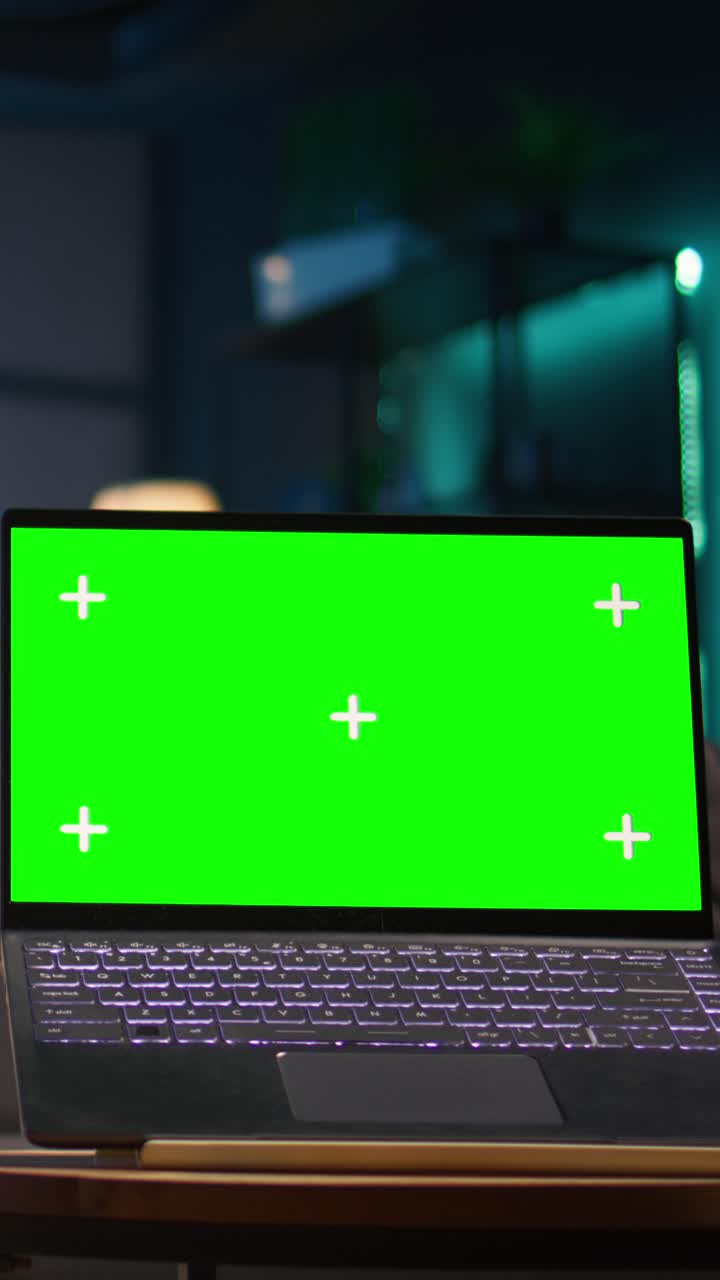 Laptop with Green Screen Display on Desk in Dark Room
