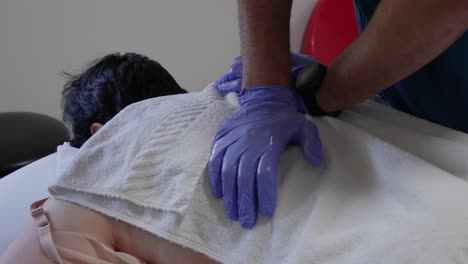 therapist presses down on patient's upper back through a towel during a massage session