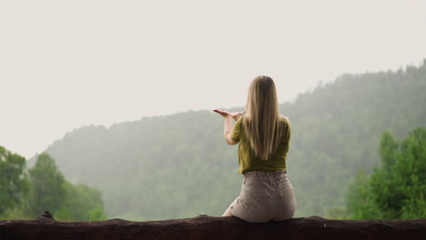 woman with loose hair reaches hands to catch rain drops spending time at highland eco resort on