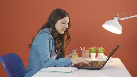 mujer joven mirando la computadora portátil contando dinero.