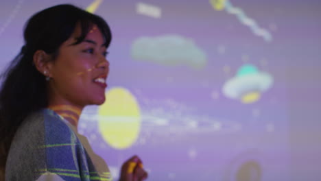 maestra dando lección de astronomía en la escuela de pie en la parte delantera de la clase con la proyección del sistema solar 3
