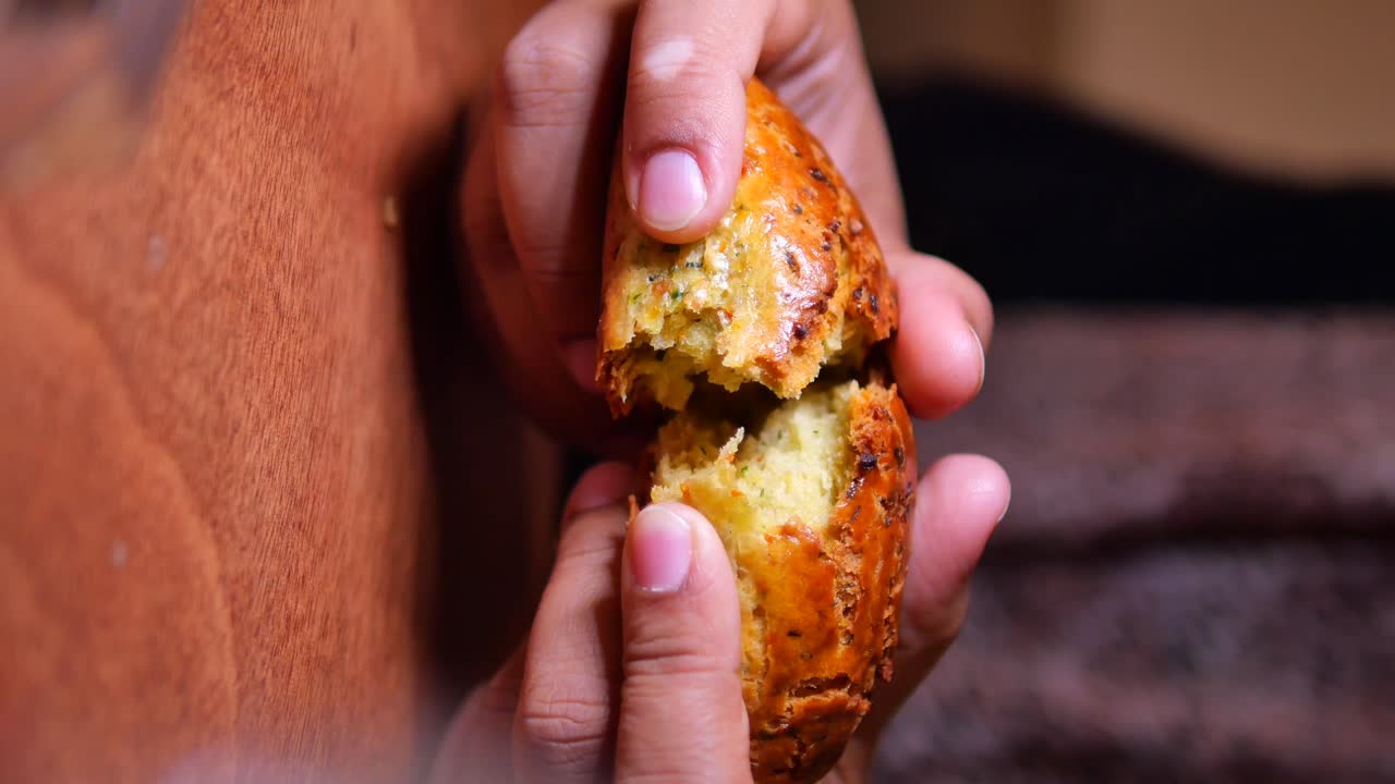 Close-up of hands breaking a muffin