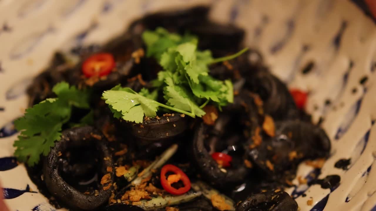 Primo piano di un piatto di frutti di mare scuro all'inchiostro di seppia servito in una ciotola decorativa a motivi