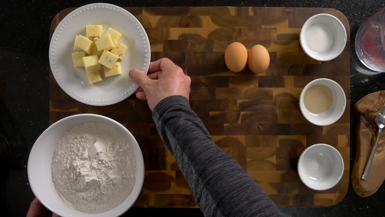 Showing bread baking ingredients from an overhead view. Including flour, sugar, yeast, salt, eggs and water