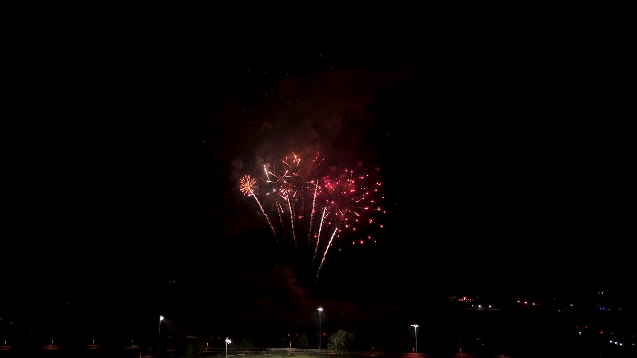los fuegos artificiales iluminan el cielo nocturno sobre la ciudad el 4 de julio - avión no tripulado volando hacia adelante