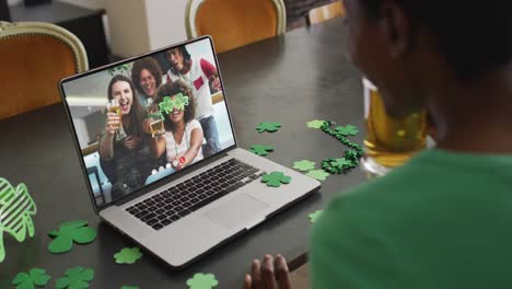 Sonriente-Grupo-Diverso-De-Amigos-Con-Cerveza-Usando-Artículos-Con-Forma-De-Trébol-En-Videollamada-En-Una-Computadora-Portátil