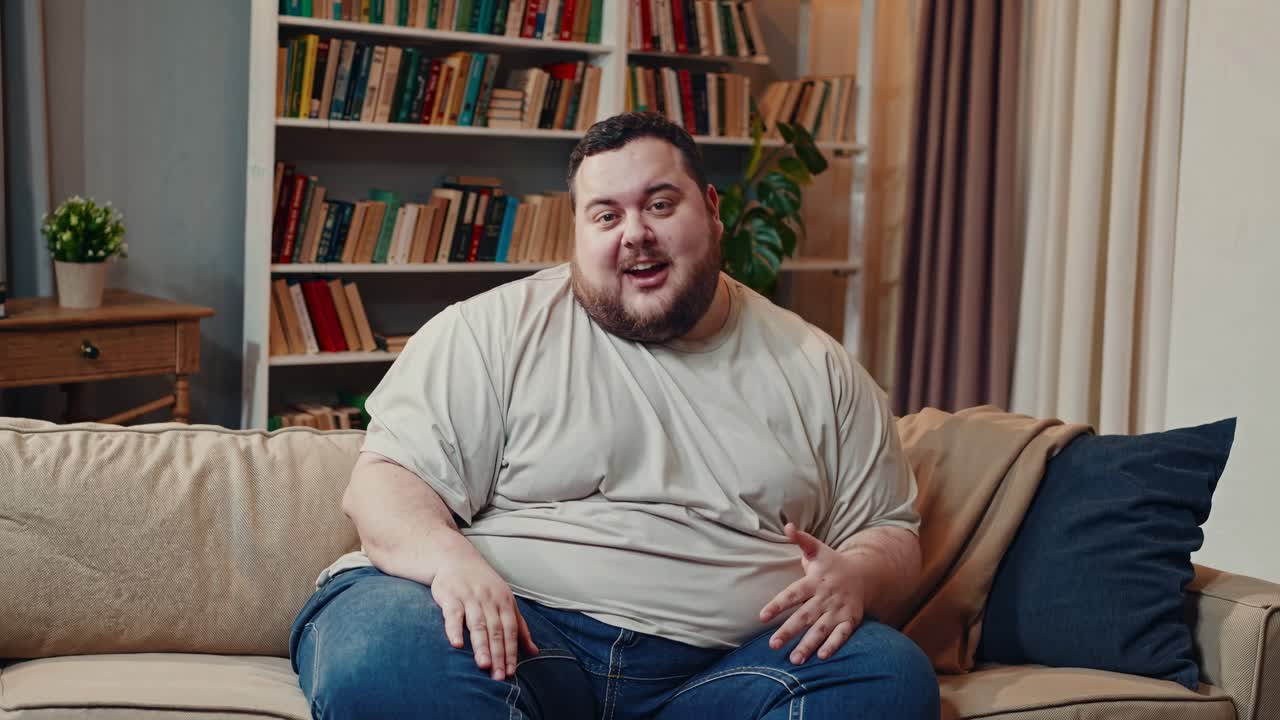 Casual video chat setting with a man on a sofa, mid-shot angle