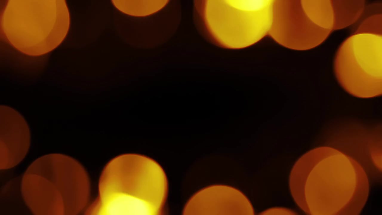 Varma gyllene bokeh-ljus som framträder och tonas ut på svart bakgrund