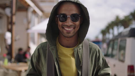 portrait-of-handsome-hispanic-man-smiling-happy-on-sunny-beachfront-wearing-hoodie