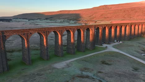 arches of railway bridge illuminated by winter sunrise light with glowing background hill