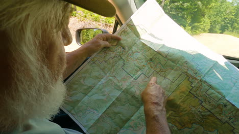 an elderly man tracing a hiking trail on a map, traveling the traditional way