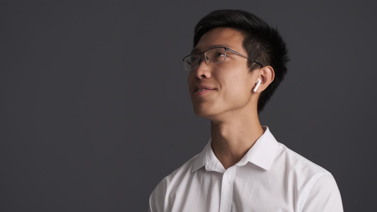 이어폰을 입은 아시아인 남자가 전화로 얘기하고 있어요.