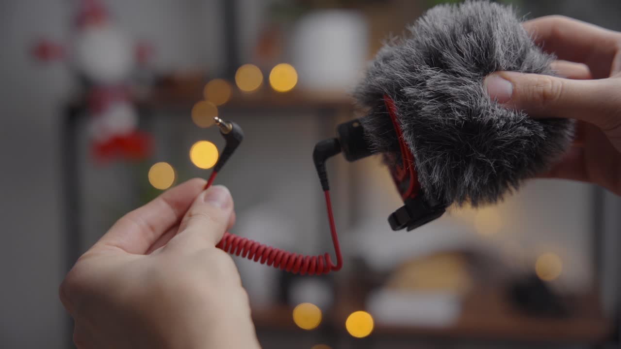 흐릿한 배경에 방향성 샷건 마이크를 손에 쥐고 있습니다.