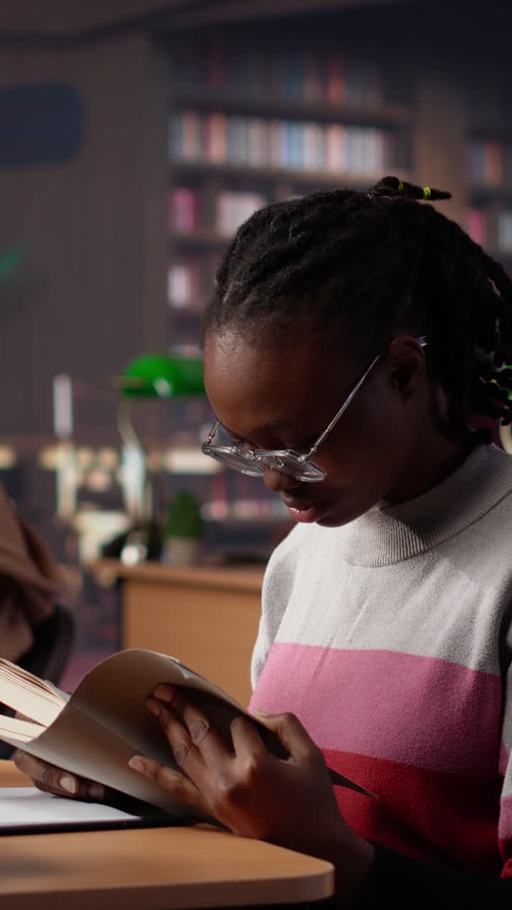 Vertical video black girl reading books and handwritten class notes right before the exam