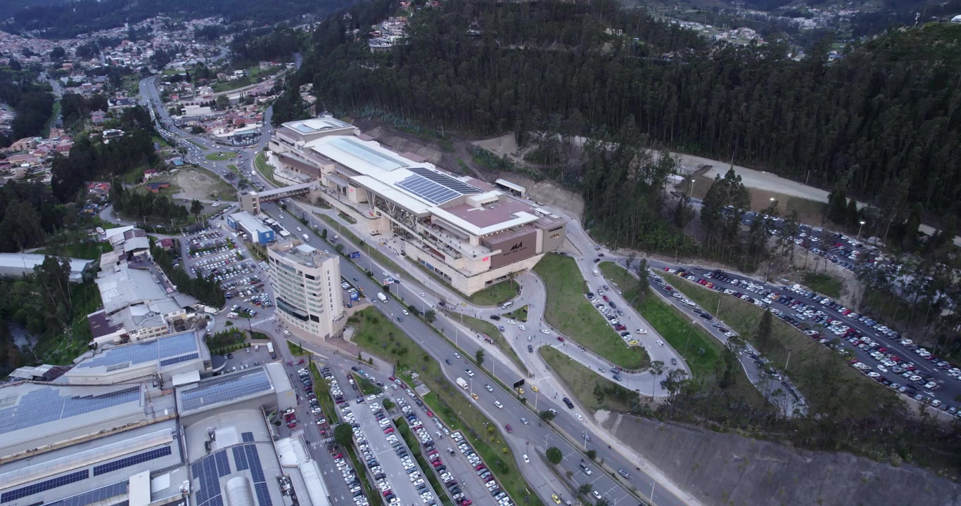 Cuenca, Ekvador'daki Mall del Alto alışveriş merkezinin üzerinden uçan muhteşem havadan drone görüntüleri, modern mimariyi ve çevresindeki güzel şehir manzarasını güneşli bir günde sergiliyor