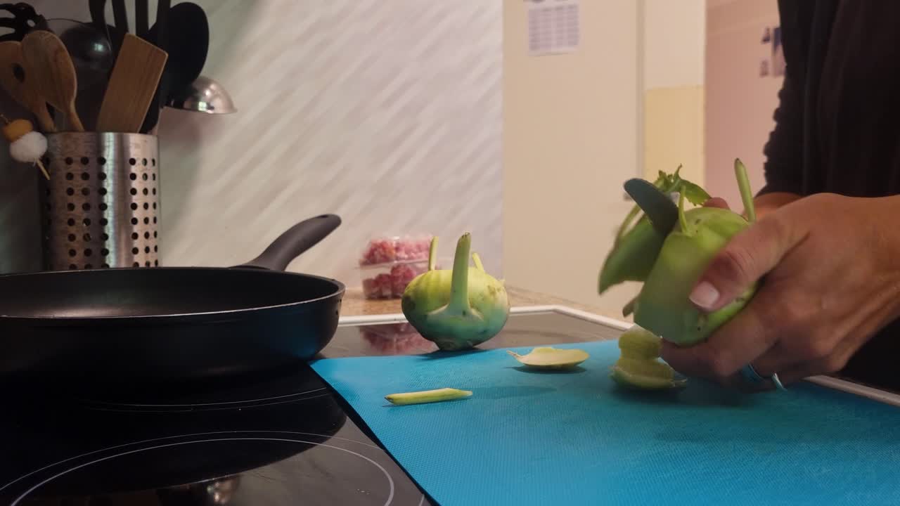 Close-up of woman slicing kohlrabi (cabbage turnip) in her cozy kitchen, preparing a healthy meal. Everyday life, home cooking and fresh vegetables in focus