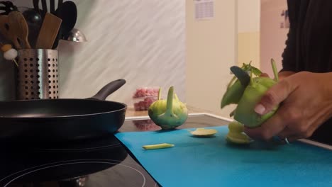 close-up of woman slicing kohlrabi (cabbage turnip) in her cozy kitchen, preparing a healthy meal. everyday life, home cooking and fresh vegetables in focus