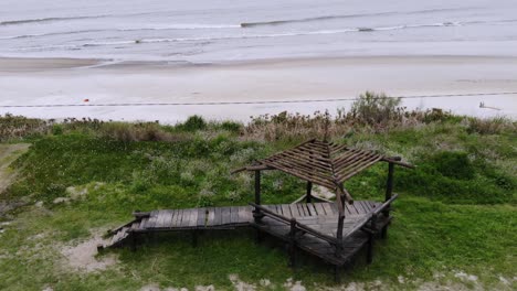 video aereo de una estructura de madera ubicada en la costa con la playa detras