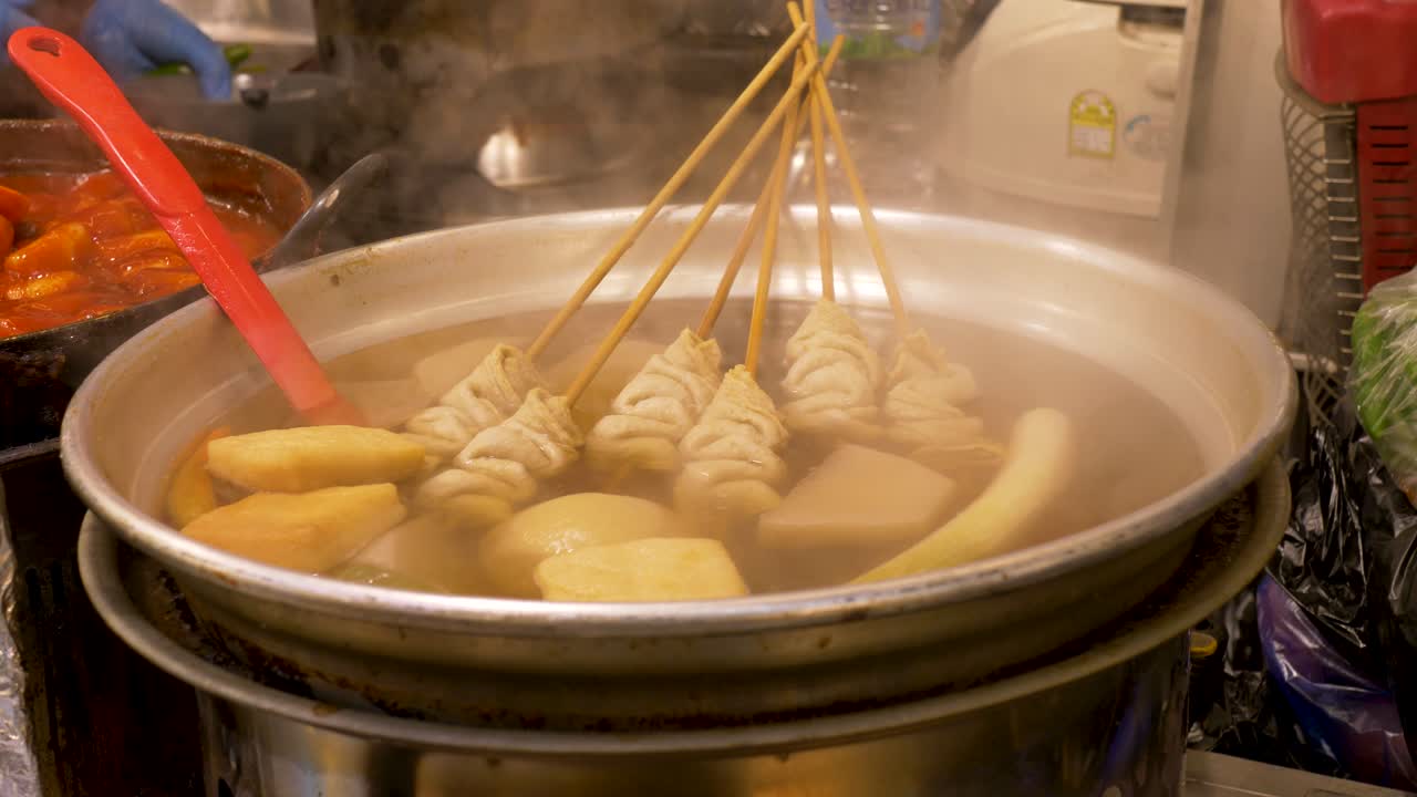 Gros plan au ralenti du bouillon de soupe Eomukguk Odeng avec des brochettes de gâteaux de poisson cuisant dans une grande marmite remplie d'eau chaude, aux marchés nocturnes de street food de Gwangjang, dans la ville de Séoul, Corée du Sud. Cuisine asiatique.