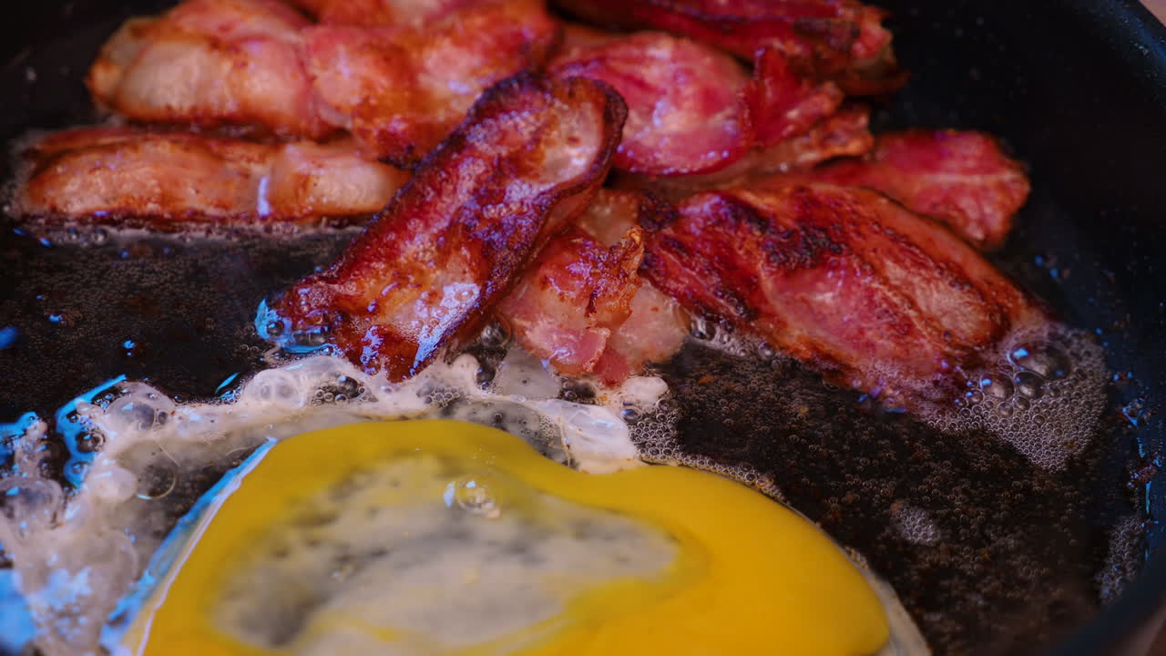 Frying crispy bacon and an egg in a pan