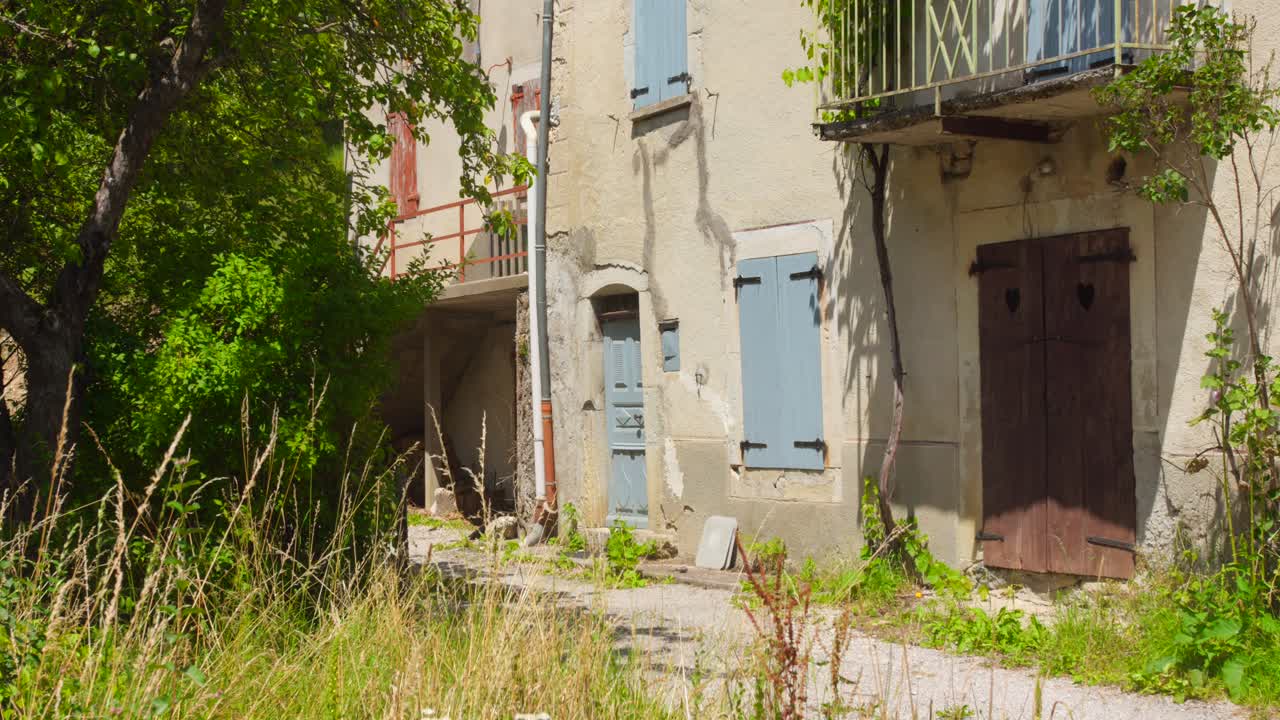 Old house with pastel shutters in a quiet, sunny French village street scene