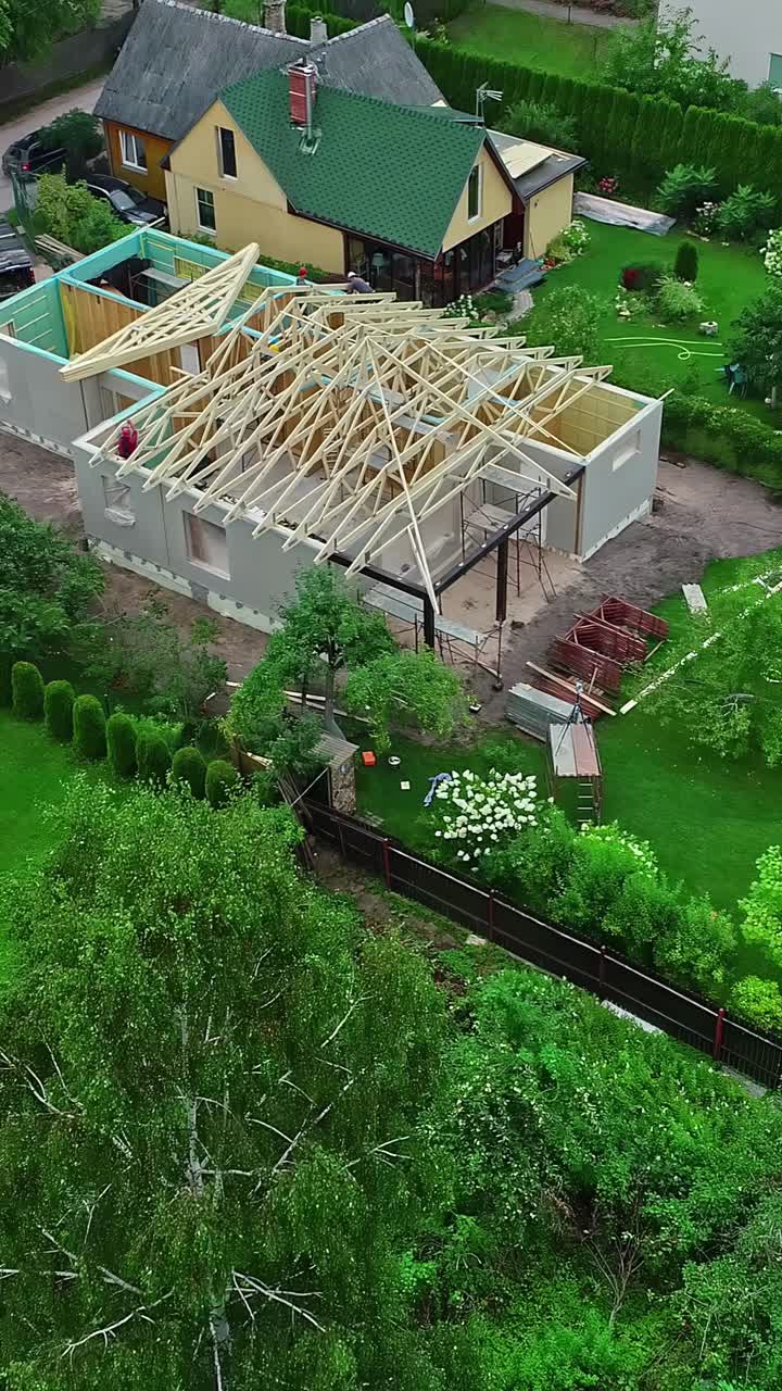 Drone pullback over wooden house framing in suburban residential area with grid layout