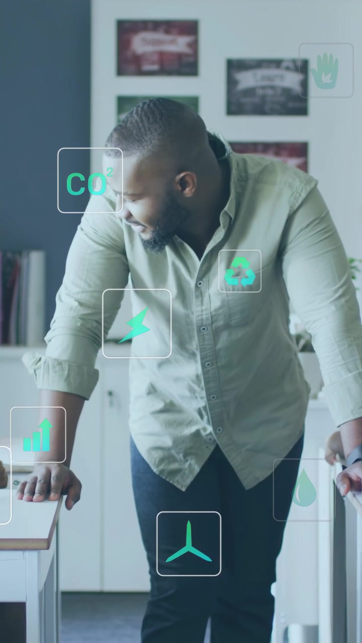 Vertical video: Man leaning on desks, responding to appearing CO2 and energy icons, reviewing data